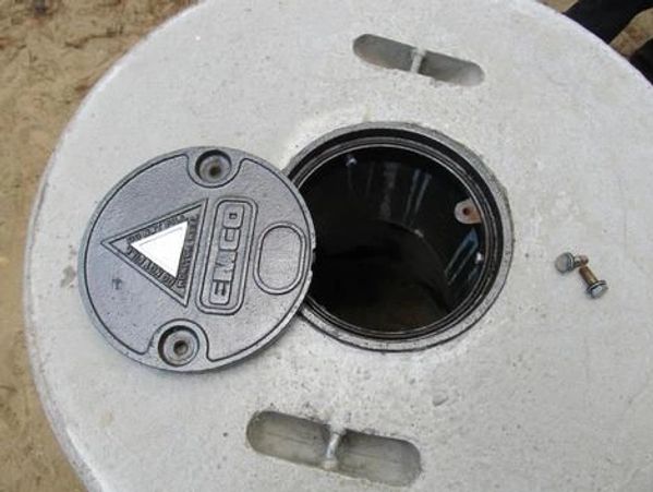 A round, weathered concrete platform with a central hole and a small metal bolt