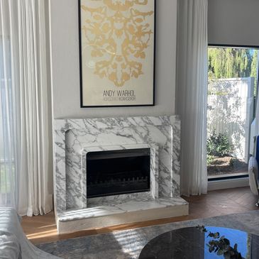 Modern living room with a marble fireplace and Andy Warhol artwork.