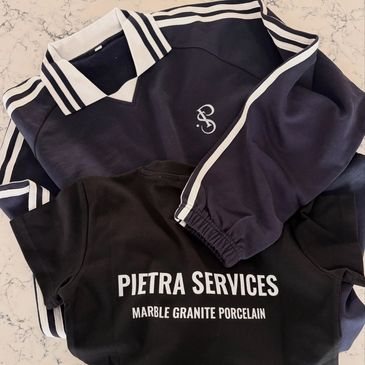 Two folded shirts, one with stripes, the other branded Pietra Services.