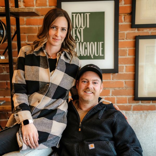 Couple posing nicely indoors against brick wall.