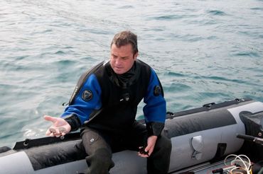 Bradley Williamson holding several silver coins recovered from shipwreck - sunken treasure.