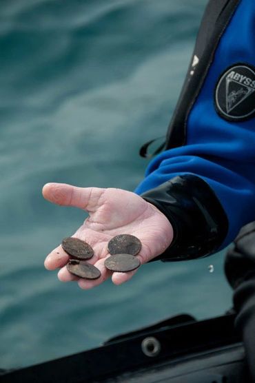 Bradley Williamson with silver coins from shipwreck in Canada.