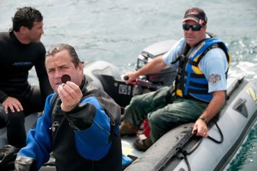 Bradley Williamson holding silver coin recovered from shipwreck in Canada.