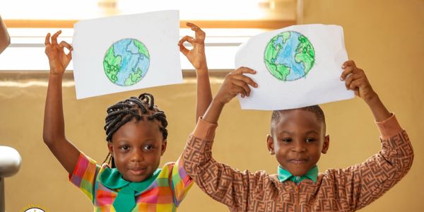 Two children holding drawings of the Earth.
