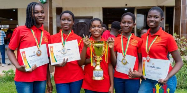 Group of girls in red shirts holding certificates and a trophy.
