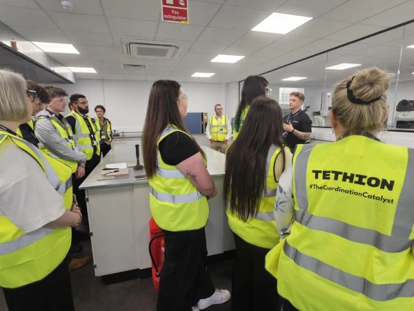 Group of people in high-visibility vests in a lab or workshop.
