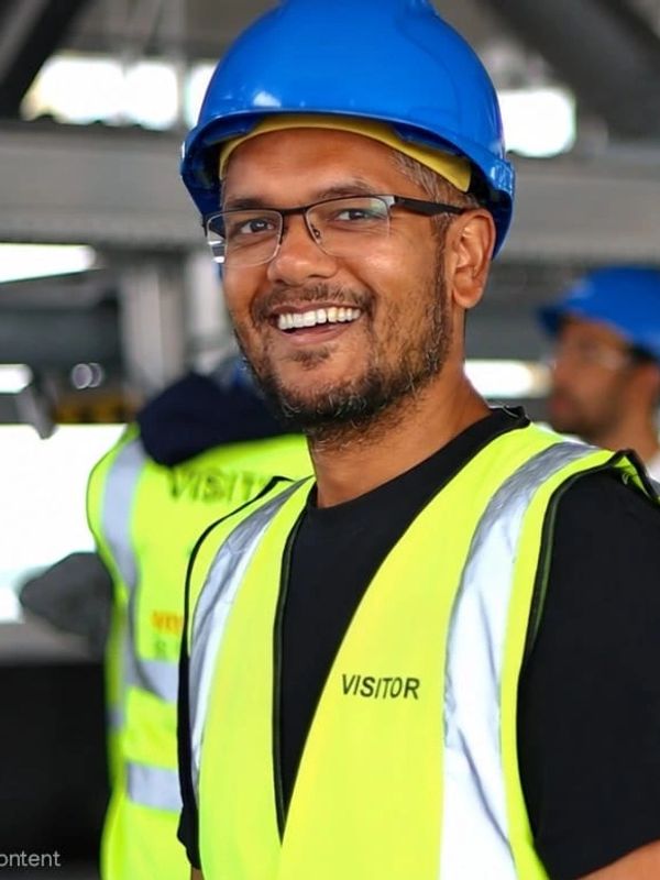 Smiling man in safety vest and blue helmet.