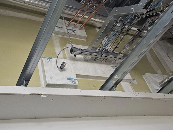 Ceiling with exposed pipes and insulation panels.