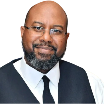 Smiling man with glasses and a beard wearing a black vest and tie.