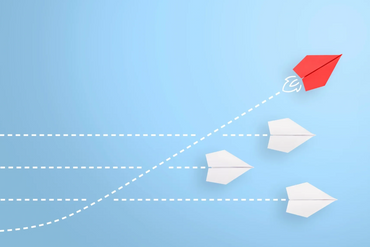 Red paper airplane soaring above white ones, symbolizing innovation.