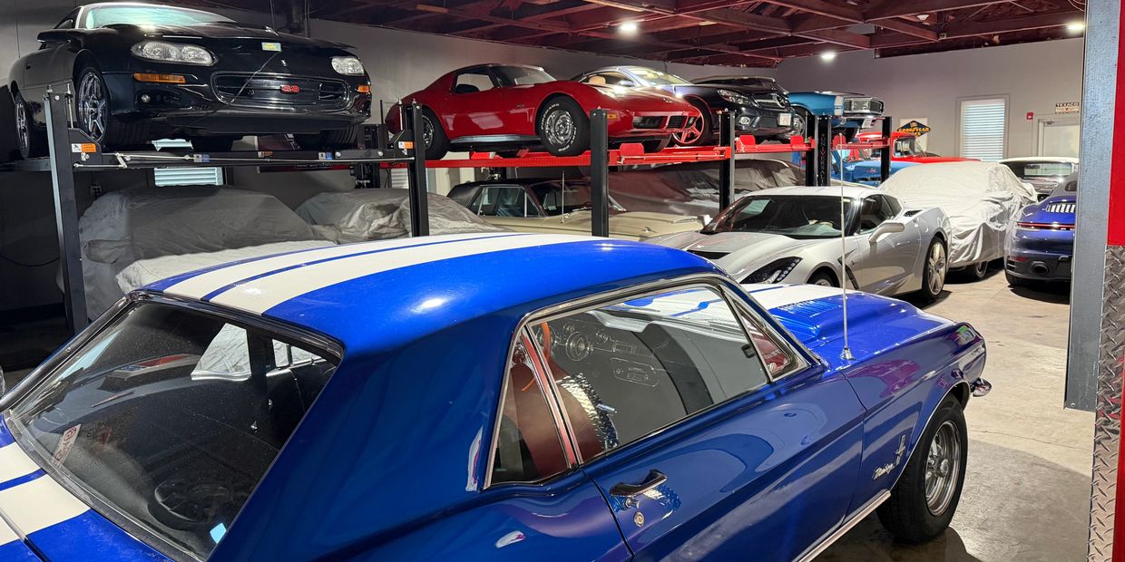 Classic and modern cars stored in a spacious garage with lifts.