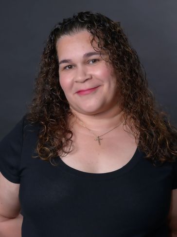 Smiling woman with curly hair in a black top.