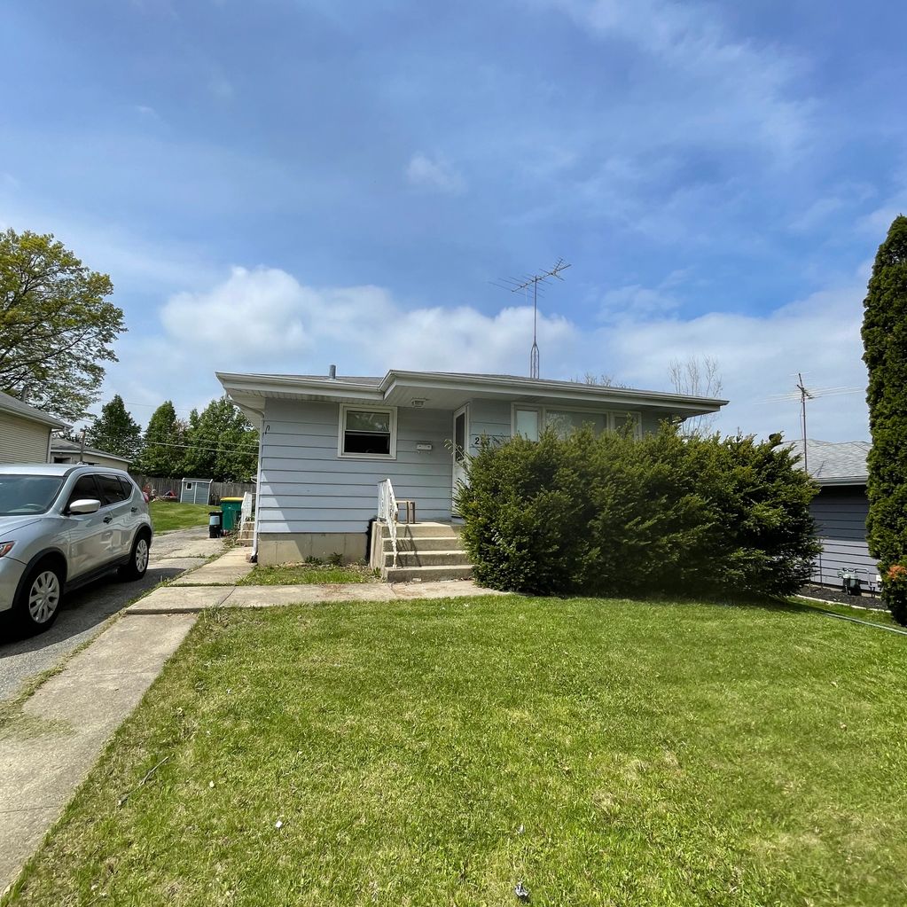 Small single-story house with a green lawn and a silver car parked in the driveway.