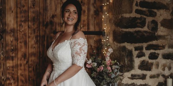 Bride in lace wedding dress smiling indoors.