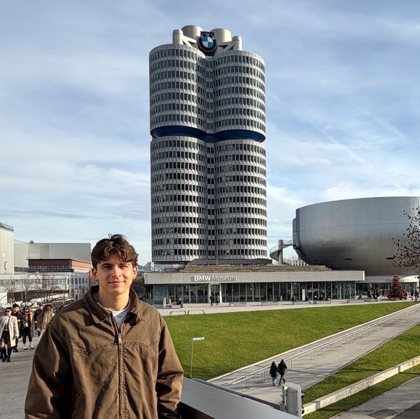 Young man standing in front of the BMW Museum in Munich on a clear day.