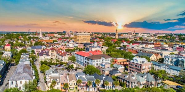 A vibrant cityscape at sunset with diverse architecture and greenery.