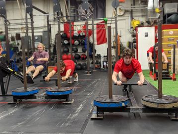 hockey team athletes pushing sleds in a team training session