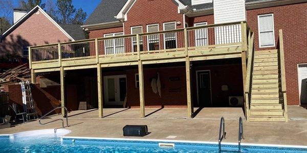 New wooden deck above a backyard pool area.