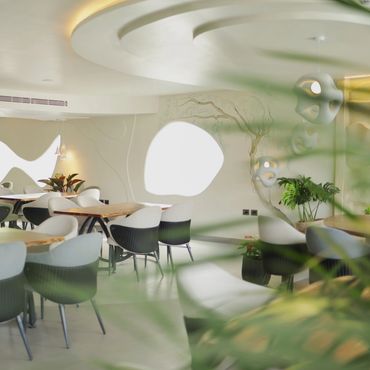 Modern cafe interior with organic shapes and greenery.