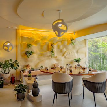 Modern dining room with unique lighting and lush greenery.