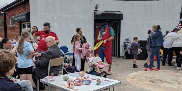 Community event outside a church with families and a clown entertaining children.