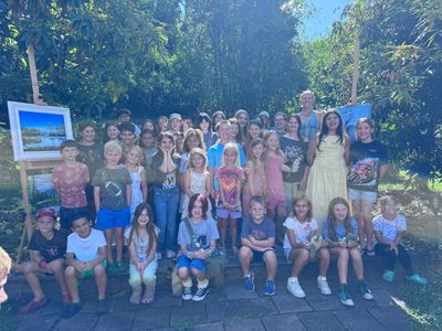 Large group of children and adults posing outdoors on a sunny day.