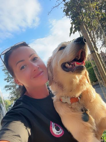 Woman smiling with her happy golden retriever dog on a sunny day.