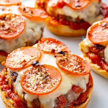 Mini cheeseburger pizzas topped with pepperoni and herbs on a plate.