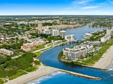 Aerial view of a coastal city with beaches, waterways, and buildings under a clear blue sky.