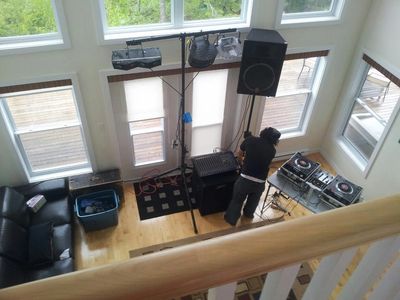 Person setting up DJ equipment in a room with large windows.