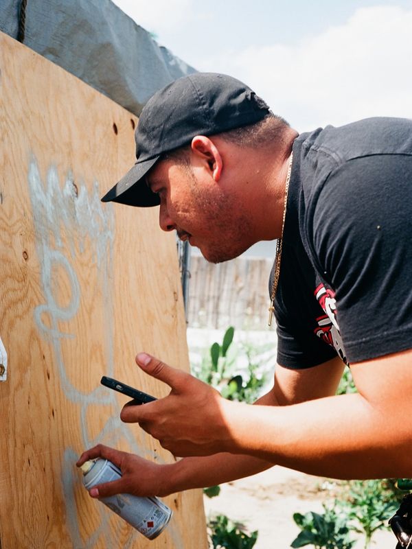 KOPS the artist paints a murals using a reference on his iPhone and a spray can for sketching