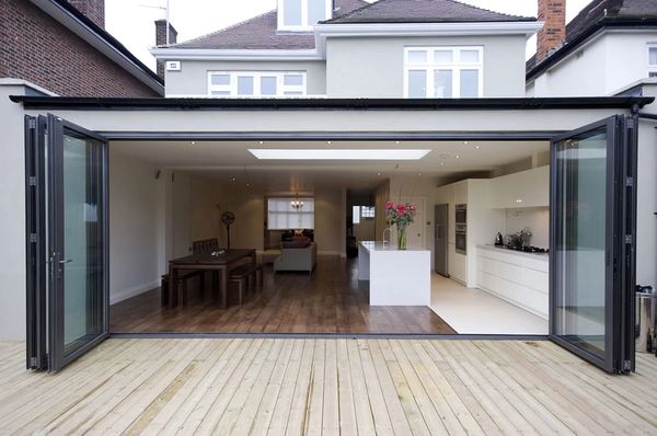 Modern open-plan kitchen and dining area with large folding glass doors to outdoor deck.