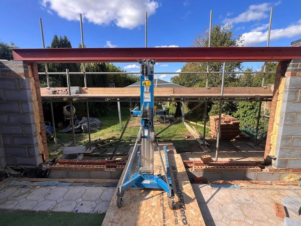 Construction site with steel beam and scaffolding under clear blue sky.