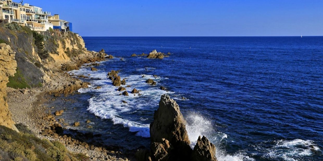 Rocky coastline with waves and houses.