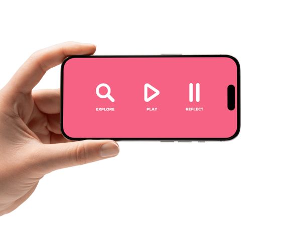 Hand holding smartphone displaying explore, play, and reflect icons on pink screen.