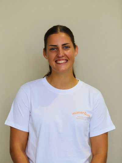 Smiling woman in a white Momentum t-shirt against a plain background.