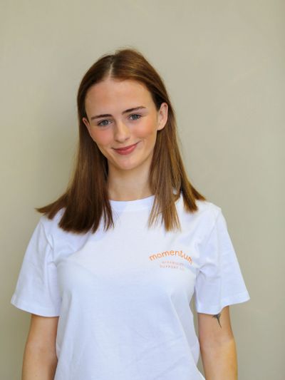 Young woman with long brown hair wearing a white T-shirt smiling.