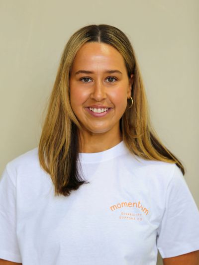Smiling woman with blonde hair wearing a white Momentum t-shirt.