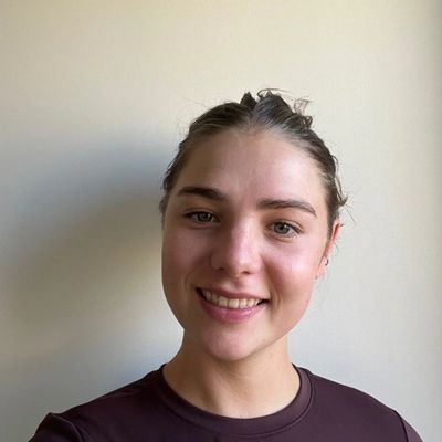 A young woman smiling against a plain light background.