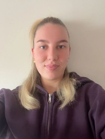 Young woman with blonde hair in a purple hoodie.