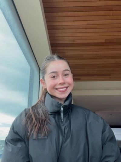Smiling young woman in black jacket indoors.