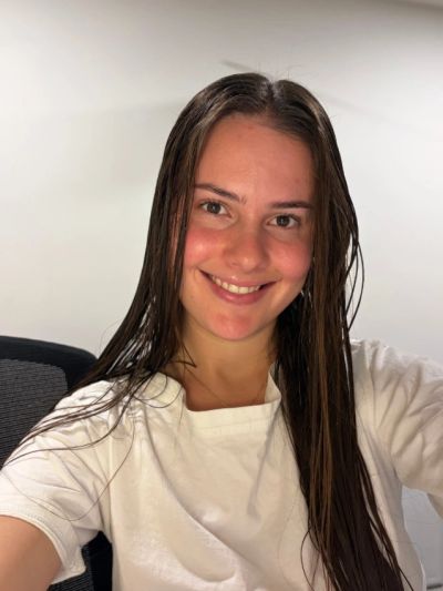 Smiling young woman with wet hair in a white shirt.