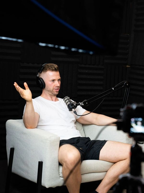Man in white shirt and headphones recording a podcast in a studio.