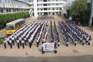 Students standing in formation holding a banner in a school courtyard.