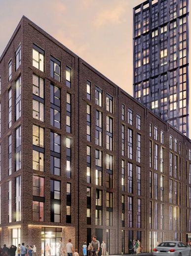 Modern brick and glass building at sunset with people and cars nearby.