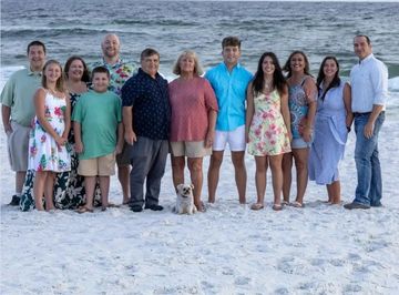 Family posing on the beach with a small dog.