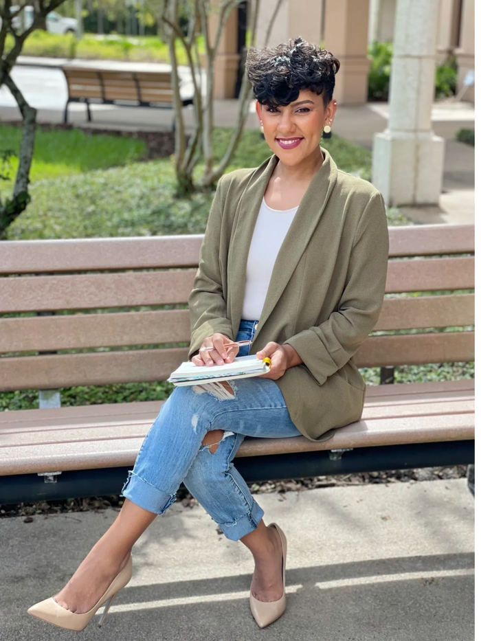 Coach Janice sitting on a bench holding a notebook