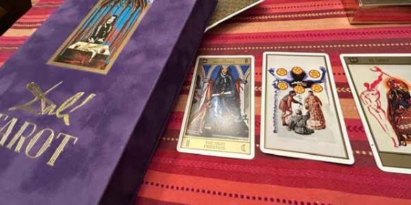 Tarot cards and a purple tarot box on a striped surface.