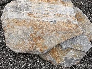 Large beige and gray rock on gravel.
