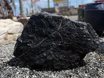 A large piece of black coal on gravel.